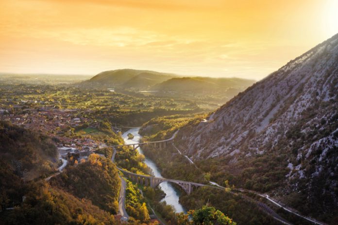 Die berühmte Eisenbahnbrücke über die Soča/Isonzo (im Vordergrund) bei Solkan mit der Stadt Nova Gorica im Hintergrund. Foto: Adobe Stock
